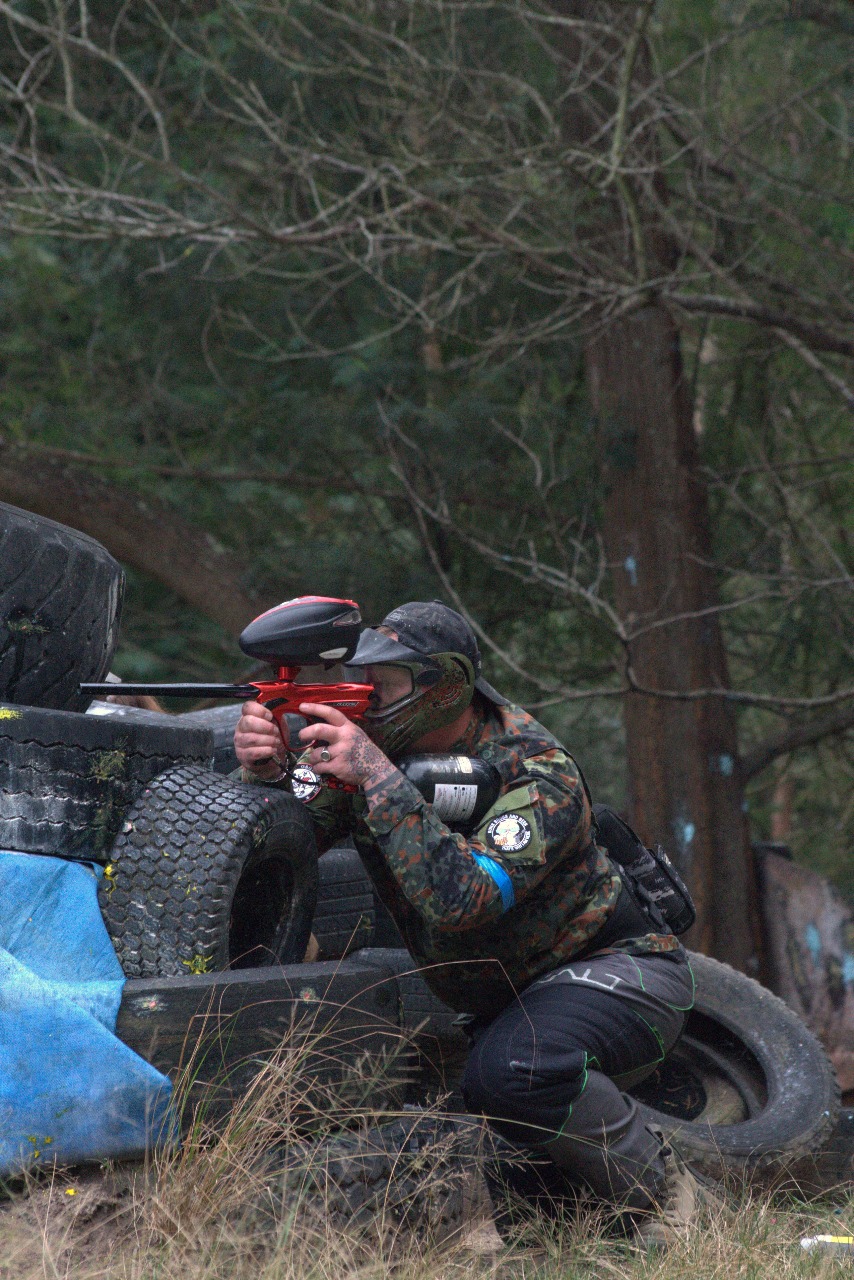 Paintball player aiming a marker from behind cover